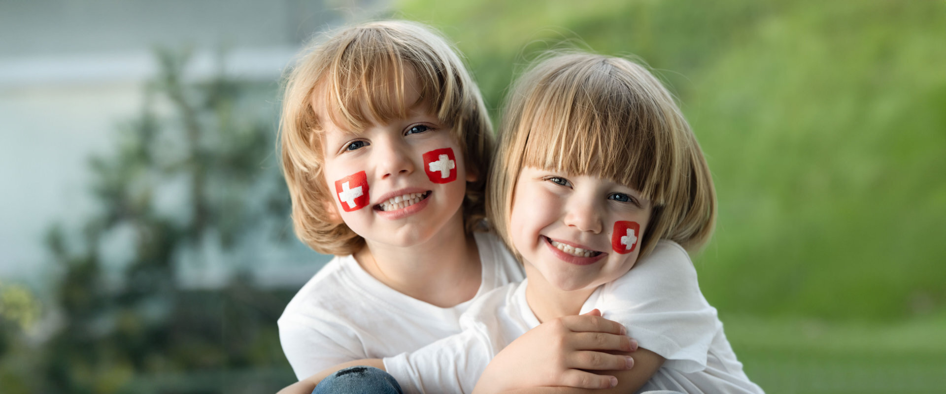 zwei Kinder mit Schweizer Flagge auf der Wange