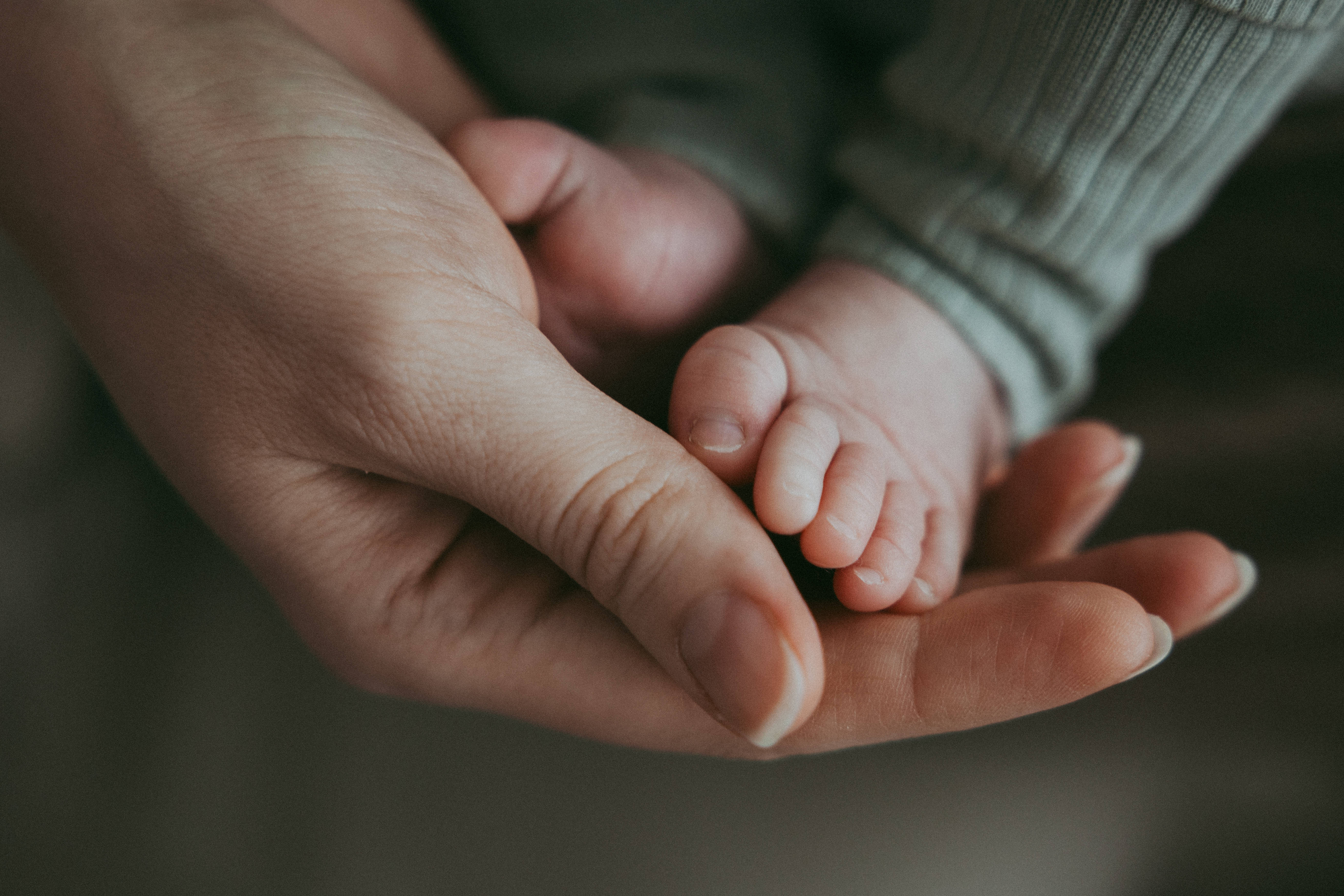 Nahaufnahme der Hand der Mutter, die die Beine des Babys hält