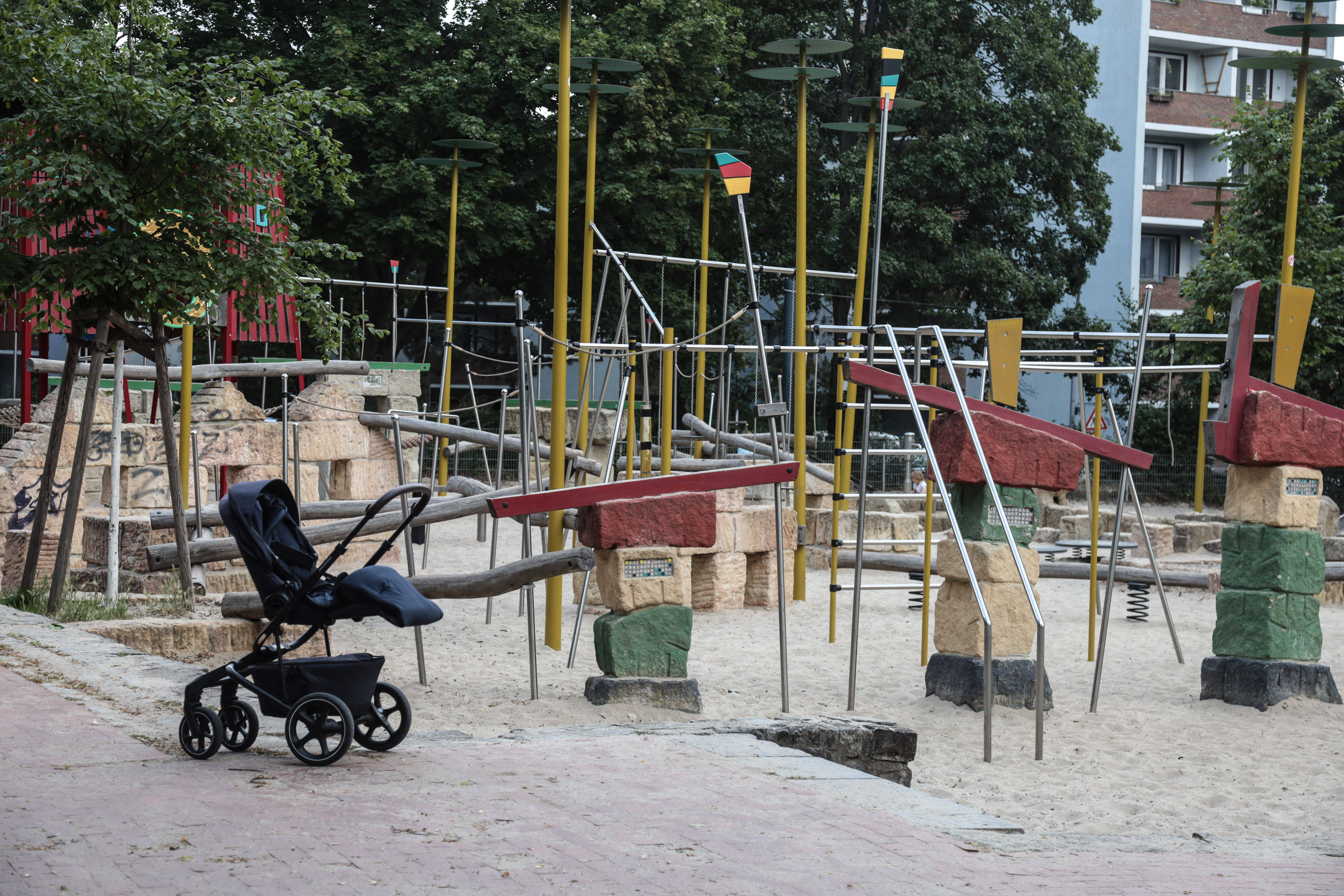 Ein leerer Kinderwagen auf einem Spielplatz.