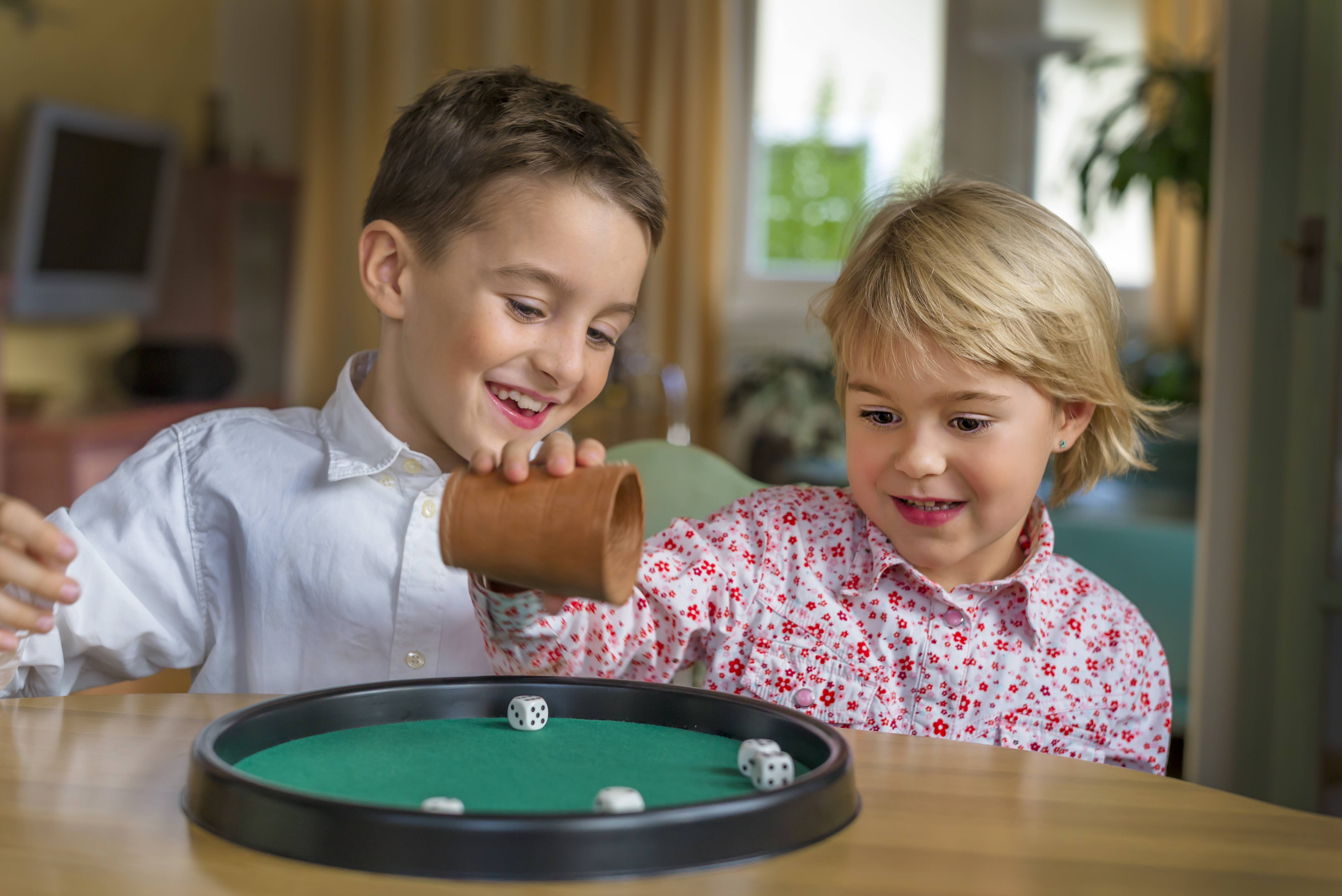 Bruder und Schwester spielen zusammen ein Würfelspiel 