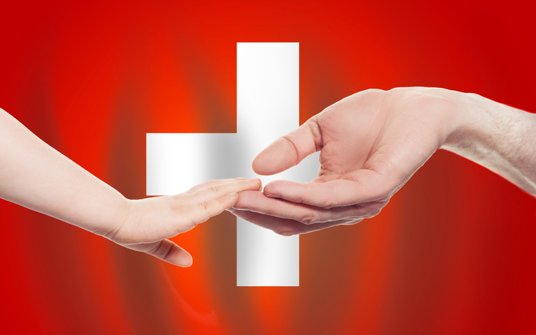 Mann und Kind reichen einander die Fingerspitzen Hintergrund Flagge Schweiz
