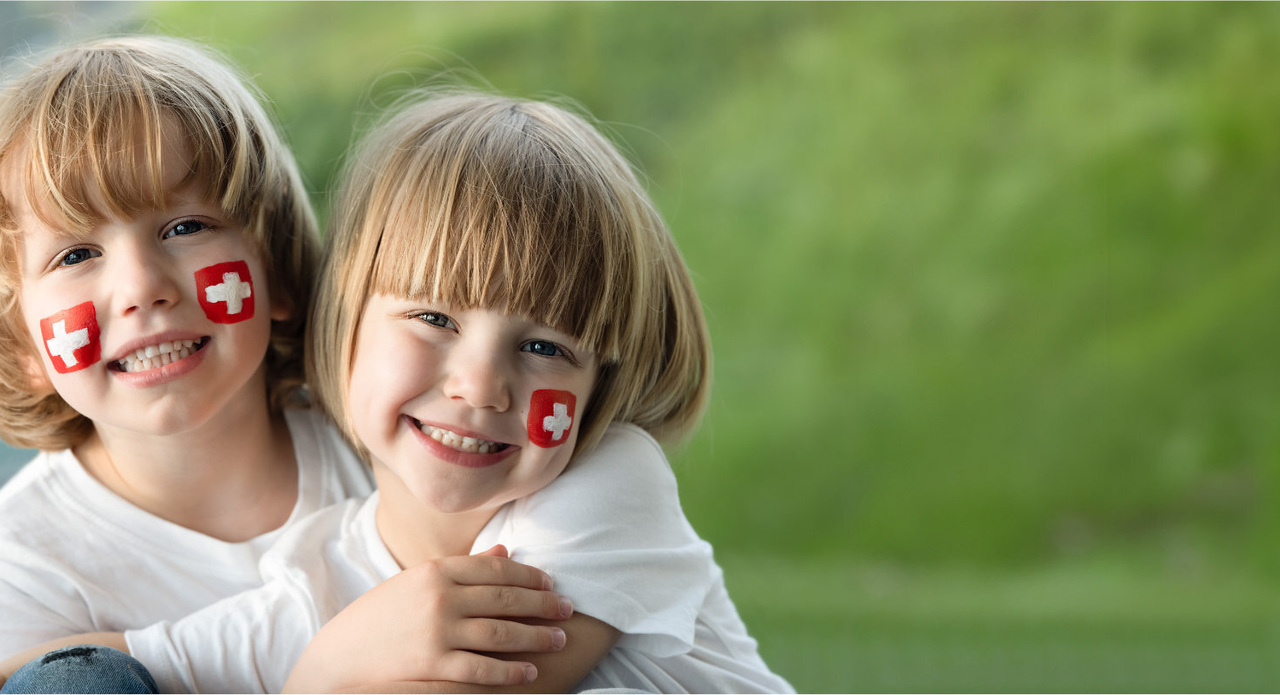 zwei Kinder mit Schweizer Flagge auf der Wange